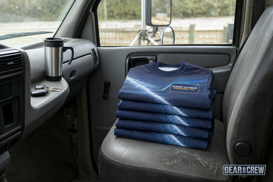 Five identical printed work shirts stacked on the passenger seat of a work truck